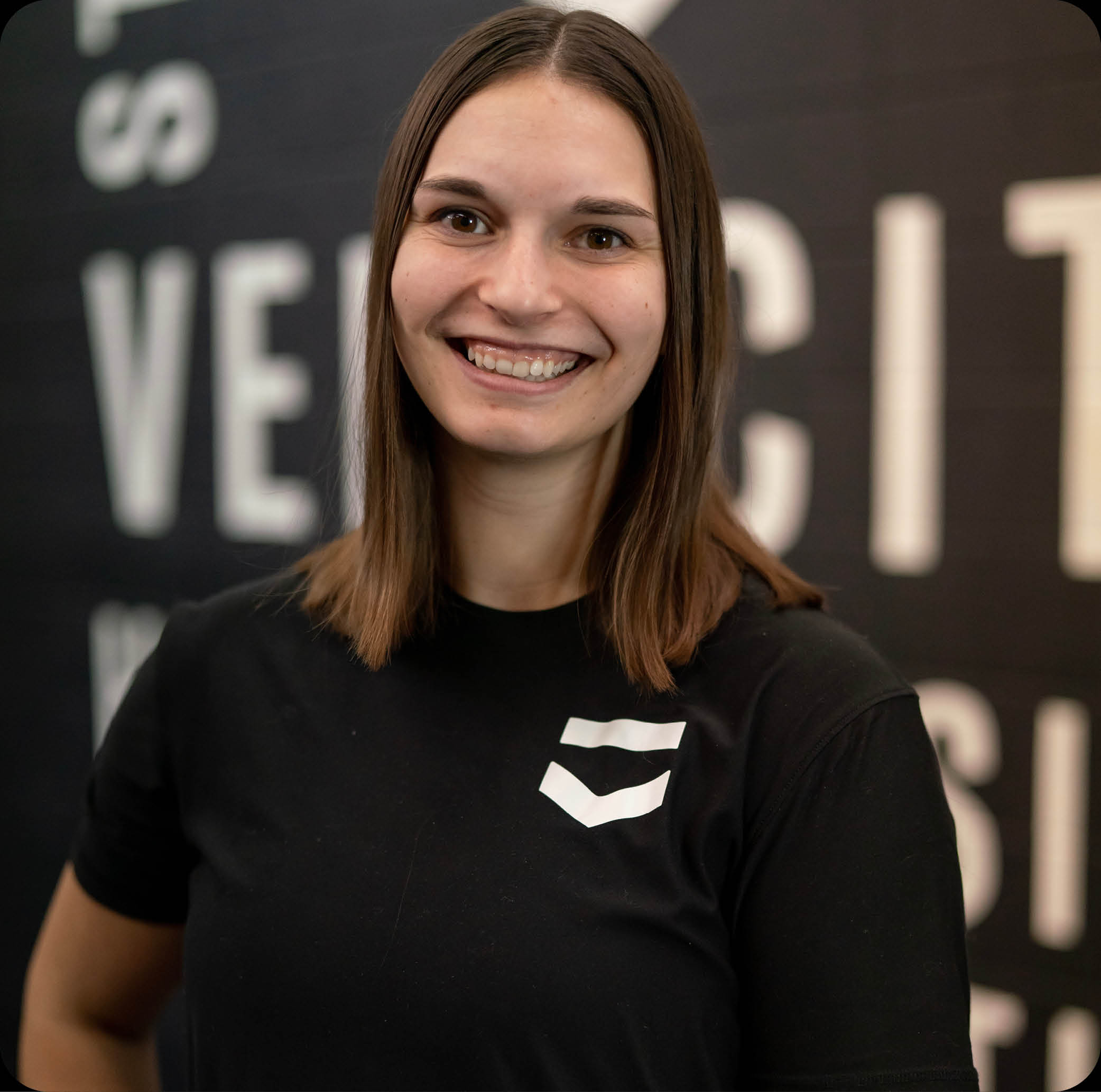 brunette woman trainer wearing a black t-shirt with the velocity logo